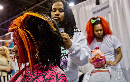 Mechele Williams (left) has her hair styled by Travis White as Antoine Wright (right) styles Aretha Dix's hair during the 2015 Bronner Bros. International Beauty Show at the Georgia World Congress Center in Atlanta on Sunday, February 22, 2015. 