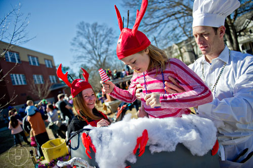 Mike Murphy (right) lifts his daughter Teagan into a crawfish boiling pot as they prepare for the start of the Mead St. Mardi Gras parade in Decatur on Saturday, February 7, 2015.