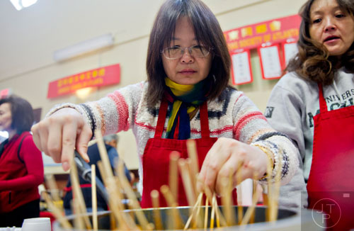 Qing Tan (center) dips freshly made fish balls into a pot of sauce during the Chinese Lunar New Year celebration in Chamblee on Saturday, February 21, 2015.