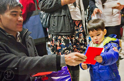 Tian Chang (left) hands a new years gift to his nephew Enoch Lee during the Chinese Lunar New Year celebration in Chamblee on Saturday, February 21, 2015. 