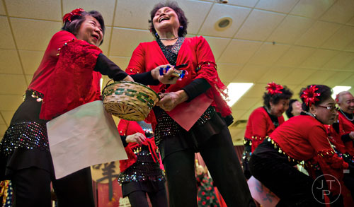 Lee Phonge (left) and Zhang Xiao reach into a basket to throw candy into the crowd after performing on stage during the Chinese Lunar New Year celebration in Chamblee on Saturday, February 21, 2015.