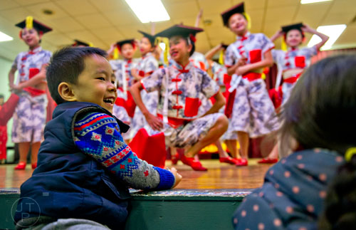 Justin Lin (left) smiles as members of the Atlanta Chinese Dance Company perform on stage during the Chinese Lunar New Year celebration in Chamblee on Saturday, February 21, 2015. 