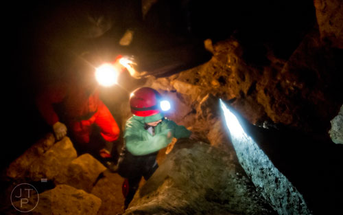 Doug Carson (left) follows behind six-year-old Elias Chandler as they climb boulders inside Frick's Cave in Chickamauga, Ga. during the Southeastern Cave Conservancy Inc.'s open house on Saturday, February 28, 2015. 