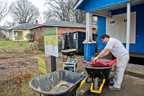 Jose Garcia looks for a tool as he works to rehab the space that used to be the front porch of the house at 880 Beryl St. in the Pittsburgh community of Atlanta on Wednesday, March 4, 2015. 