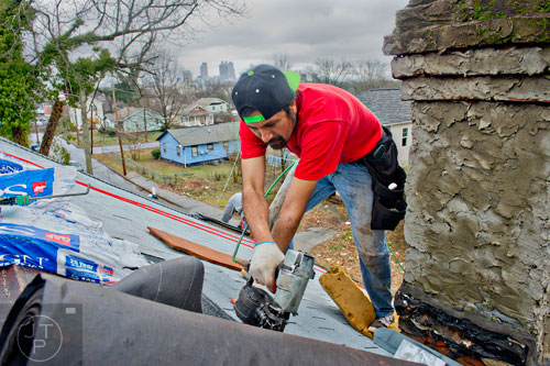 Luis Domingez makes repairs to the roof of the house at 595 Rockwell St. in the Pittsburgh community of Atlanta on Wednesday, March 4, 2015. 