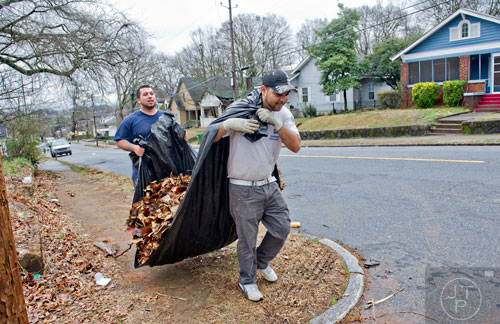 Marcos Allala (right) and Macarao Alvarado walk a pile of yard debris to a nearby dumpster as they work on one of the many homes in disrepair in the Pittsburgh community of Atlanta on Wednesday, March 4, 2015.