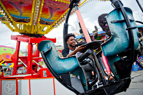 Rodney Woods (center) spins the ride as he and Ashley Miles fly around the Tornado at the Atlanta Fair on Wednesday, March 4, 2015. 