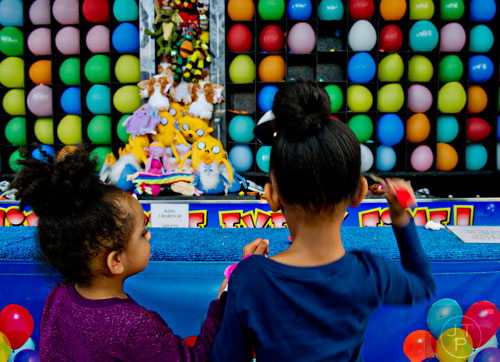 Joi McCord (left) and her sister Nyla pop balloons with darts as they play one of the games on the Midway at the Atlanta Fair on Wednesday, March 4, 2015. 