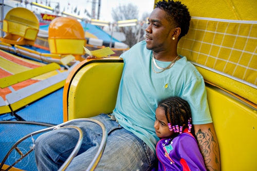 Quamaine Mullen (left) holds onto his daughter Yanna as they ride the Tilt-A-Whirl at the Atlanta Fair on Wednesday, March 4, 2015. 