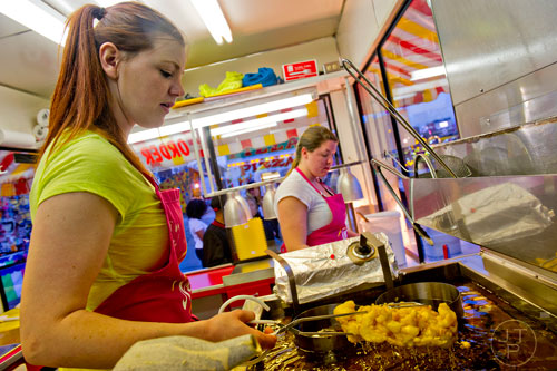 Paige Cooper (left) pulls a fresh funnel cake out of the fryer as she and Cassie Lecureux fill orders in a booth at the Atlanta Fair on Wednesday, March 4, 2015.
