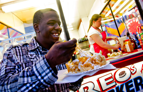 Delizha Manassa (left) takes a forkful of funnel cake as Cassie Lecureux makes a fresh one in the booth behind him at the Atlanta Fair on Wednesday, March 4, 2015.
