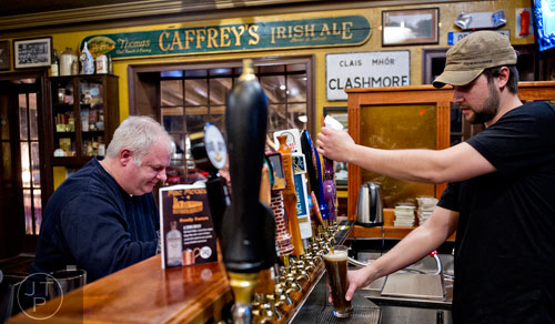 Will Stevens (right) pours beers for patrons at Mac McGee in Roswell on Friday, February 27, 2015. 