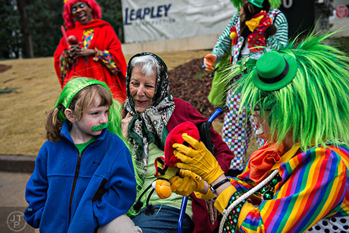 Nora MacLeod (left) sits on her grandmother Marilyn Adams' lap as they talk with Bell the Clown as they wait for the start of the 2015 Atlanta St. Patrick's Parade on Saturday, March 14, 2015. 