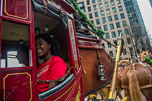 Imani Brown (left) rides in a horse drawn stage coach down Peachtree St. during the 2015 Atlanta St. Patrick's Parade on Saturday, March 14, 2015. 
