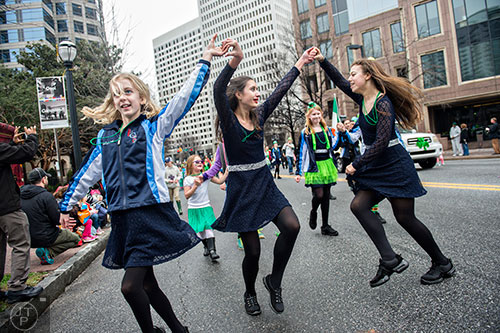 Katherine Fisher (left), Courtney Docherly and Claudia Decredico dance down Peachtree St. during the 2015 Atlanta St. Patrick's Parade on Saturday, March 14, 2015. 