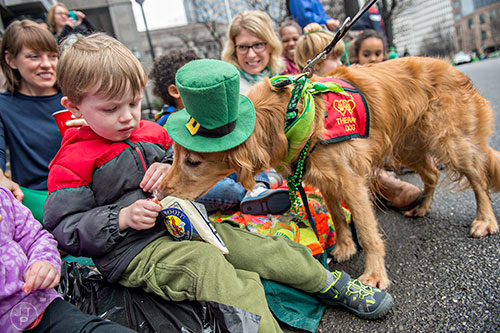 Ryder White (left) tries to keep Pearl, a golden retriever, from getting into his snack during the 2015 Atlanta St. Patrick's Parade on Saturday, March 14, 2015. 