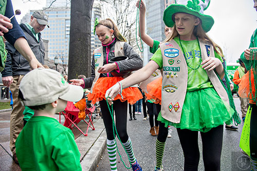 Nora Rosenfeld (right) hands William McCullough a string of beads as she walks with other Girl Scouts down Peachtree St. during the 2015 Atlanta St. Patrick's Parade on Saturday, March 14, 2015. 