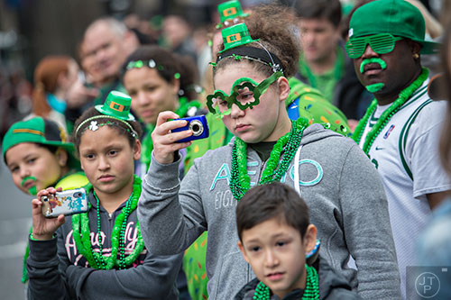 Shianne Sartain (center) and Darshay Bonner watch as the 2015 Atlanta St. Patrick's Parade makes its way down Peachtree St. on Saturday, March 14, 2015.