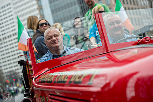 Winder Fire Lt. Tommy Evans (left) and engineer William Reidling drive an antique fire engine down Peachtree St. during the 2015 Atlanta St. Patrick's Parade on Saturday, March 14, 2015. 