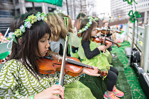 Isabel Salehbhai (left) plays the fiddle as she rides down Peachtree St. during the 2015 Atlanta St. Patrick's Parade on Saturday, March 14, 2015. 