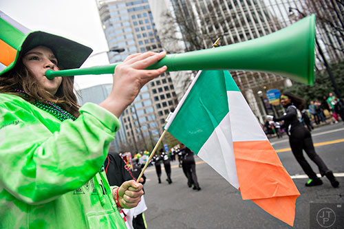 Emily McCafferty (left) blows her horn as the 2015 Atlanta St. Patrick's Parade makes its way down Peachtree St. on Saturday, March 14, 2015.