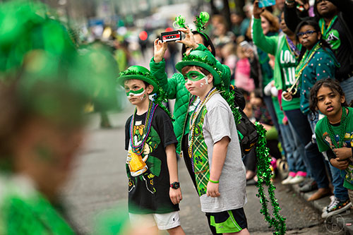 Preston Emberger (right), Chris Fitzpatrick and her son Maccoy watch as the 2015 Atlanta St. Patrick's Parade makes its way down Peachtree St. on Saturday, March 14, 2015.