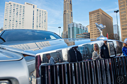Nikki Bishop (center) is reflected in the gril of a Rolls Royce Phantom during the Caffeine & Exotics Car Show at Lenox Square Mall in Atlanta on Sunday, March 15, 2015. 