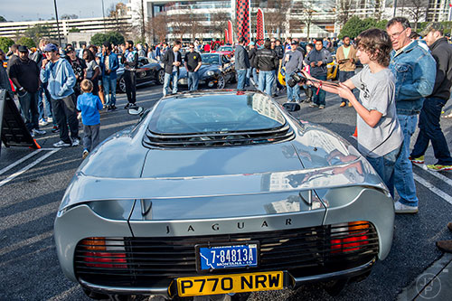 Ezra Evans (right) leans over a Jaguar XJ220 to take a photo of the engine compartment during the Caffeine & Exotics Car Show at Lenox Square Mall in Atlanta on Sunday, March 15, 2015. 