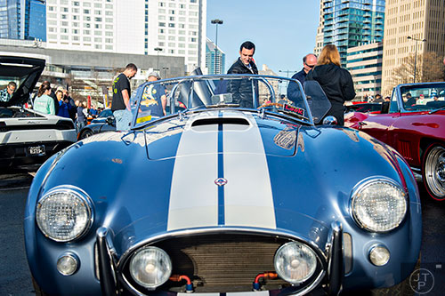 Sam Nash (center) peers over the trunk of a 427 Shelby Cobra during the Caffeine & Exotics Car Show at Lenox Square Mall in Atlanta on Sunday, March 15, 2015. 