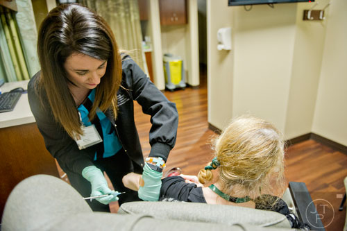 Brittany Deraney (left) holds a patient's arm as she injects her with medication at the Cancer Treatment Centers of America's Southeastern Regional Medical Center in Newnan on Friday, February 20, 2015.