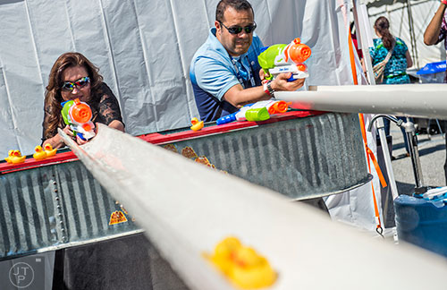 Carla Gullett (left) and Raul Gamez uses water guns to spray rubber ducks down a set of tubes during the sixth annual Beer Carnival at Atlantic Station in downtown Atlanta on Saturday, March 21, 2015.