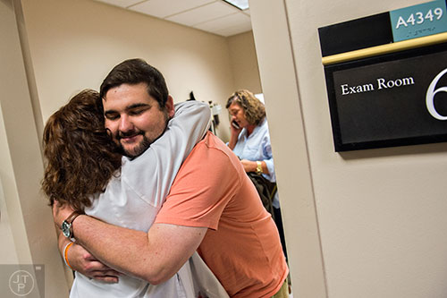 Drew Crenshaw (center) hugs nurse Debbie Cohen after completing his check up at the Emory Clinic off of Clifton Rd. in Atlanta on Friday, March 13, 2015. 