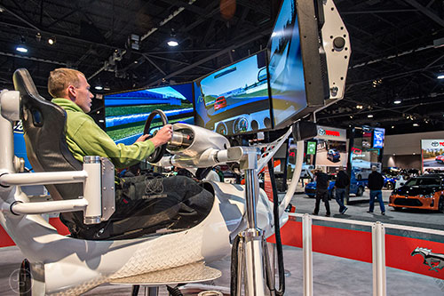 Chas Keithan (left) tests his skills in a driving simulator during the Atlanta International Auto Show at the Georgia World Congress Center on Sunday, March 29, 2015.