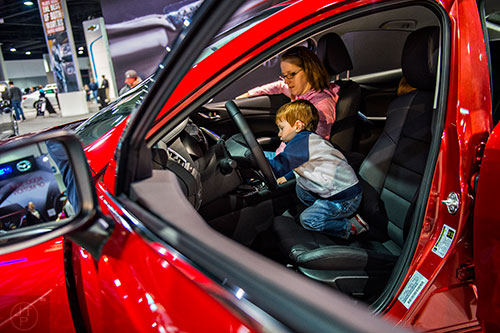 William Hoerger (right) plays in the drivers seat of a Mazda 6 next to his mother Emma during the Atlanta International Auto Show at the Georgia World Congress Center on Sunday, March 29, 2015. 