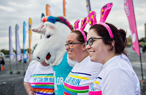 Kaenan Moreno (right) and her sisters Dekotah and Debbie have their photo taken with The Color Run mascot as they wait for the start of the race at Atlanta Motor Speedway in Hampton on Saturday, April 4, 2015. 