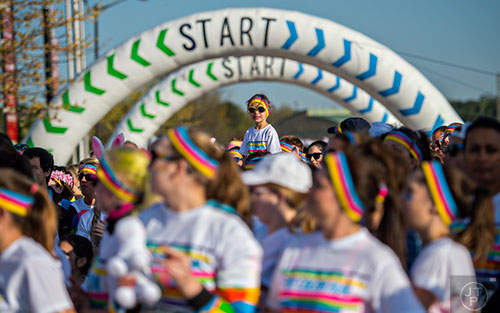 Ashley Carrigan (center) is raised on her father's shoulders as they wait for the start of The Color Run at Atlanta Motor Speedway in Hampton on Saturday, April 4, 2015.