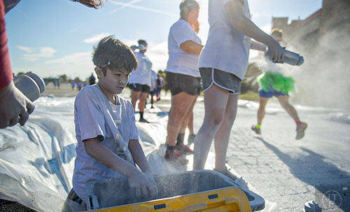 Covered in silver colored dust, Haven Maruyama (left) grabs handfuls of the powder to throw at racers during The Color Run at Atlanta Motor Speedway in Hampton on Saturday, April 4, 2015.