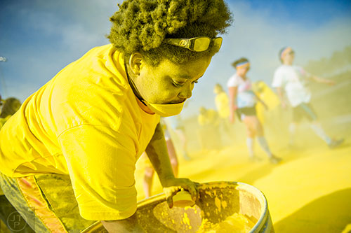 Covered in yellow colored dust, Chelesie Leath grabs handfuls of the powder to throw at racers during The Color Run at Atlanta Motor Speedway in Hampton on Saturday, April 4, 2015. 