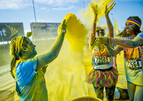 Hailee Brand (left) and other racers throw yellow colored dust into the air during The Color Run at Atlanta Motor Speedway in Hampton on Saturday, April 4, 2015. 