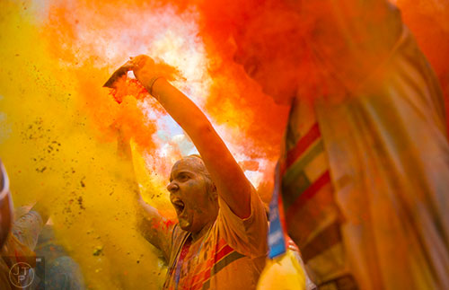 Amy Hartman (left) and Bailey Denton throw yellow and orange colored dust into the air during the after party for The Color Run at Atlanta Motor Speedway in Hampton on Saturday, April 4, 2015. 