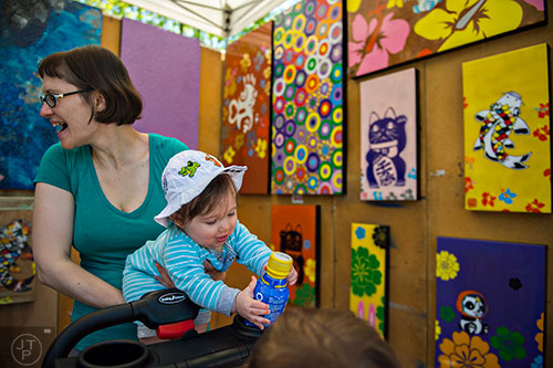 Rebekah Speiser (left) holds her son Abram as they check out John Hung Ha's artwork during the 79th annual Atlanta Dogwood Festival at Piedmont Park on Saturday, April 11, 2015. 