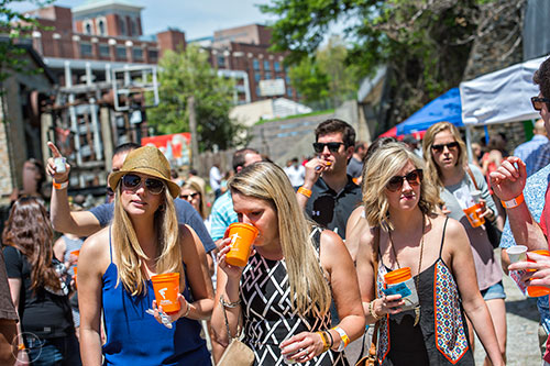 Katie Carson (left), Jill Byers and Amber Drummond carry their beers as they walk  during the Hogs & Hops Festival at The Masquerade in Atlanta on Saturday, April 11, 2015.