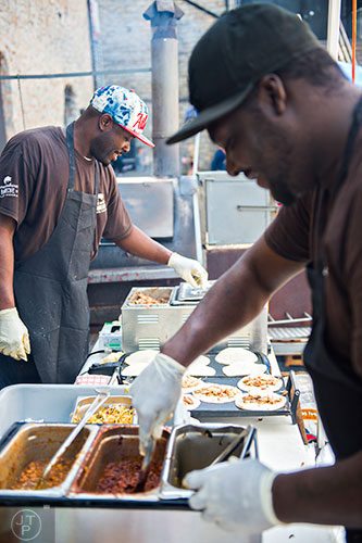 Travis Sims (left) and Demarcus Colquitt make barbeque tacos during the Hogs & Hops Festival at The Masquerade in Atlanta on Saturday, April 11, 2015. 