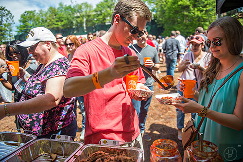 Cory King (center) pours barbeque sauce for Natalie Duren during the Hogs & Hops Festival at The Masquerade in Atlanta on Saturday, April 11, 2015. 