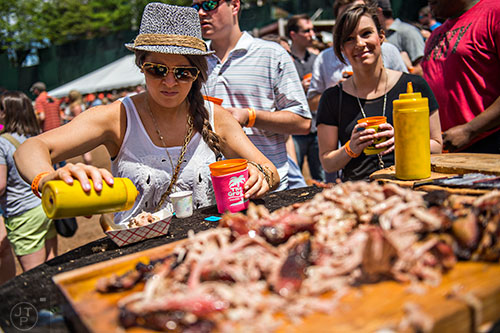 Holly Lybeer (left) pours some sauce on her barbeque during the Hogs & Hops Festival at The Masquerade in Atlanta on Saturday, April 11, 2015.
