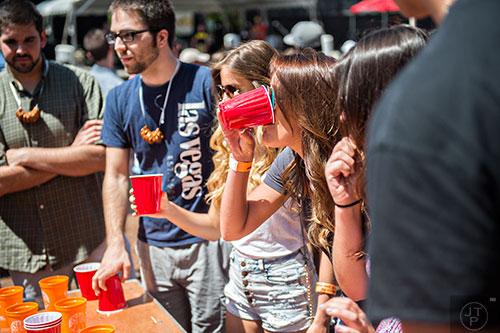 Jordyn Moerner (right) takes a drink while playing flip cup during the Hogs & Hops Festival at The Masquerade in Atlanta on Saturday, April 11, 2015. 