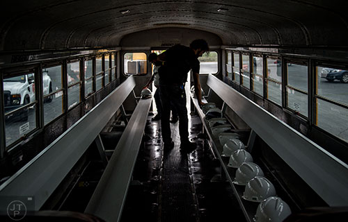 Rob Dunalewicz (right) and Aaron Coury place hardhats on the seats of a bus before a #weloveatl photowalk of the General Motors assembly plant in Doraville on Sunday, April 12, 2015. 