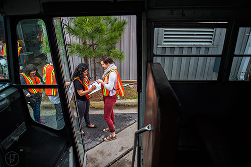 Meyly Brizuela (center) signs a release form held by Emily Schreck (right) before piling  onto a bus full of photographers that will take them into the General Motors assembly plant in Doraville during a #weloveatl photowalk on Sunday, April 12, 2015. 