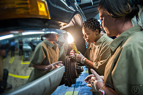 Sharonda Clifford (left) and Ashley Ritner look at the brakes on a pickup truck during automotive class at the Lee Arrendale Correctional Facility in Alto on Friday, April 10, 2015. 