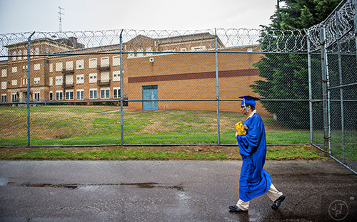 Wearing her cap and gown, Sandra Daniel walks back through security at the Lee Arrendale Correctional Facility in Alto on Friday, April 10, 2015. 